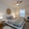 Bedroom with woven wall art, striped bedding, and ceiling fan at Denver apartments.